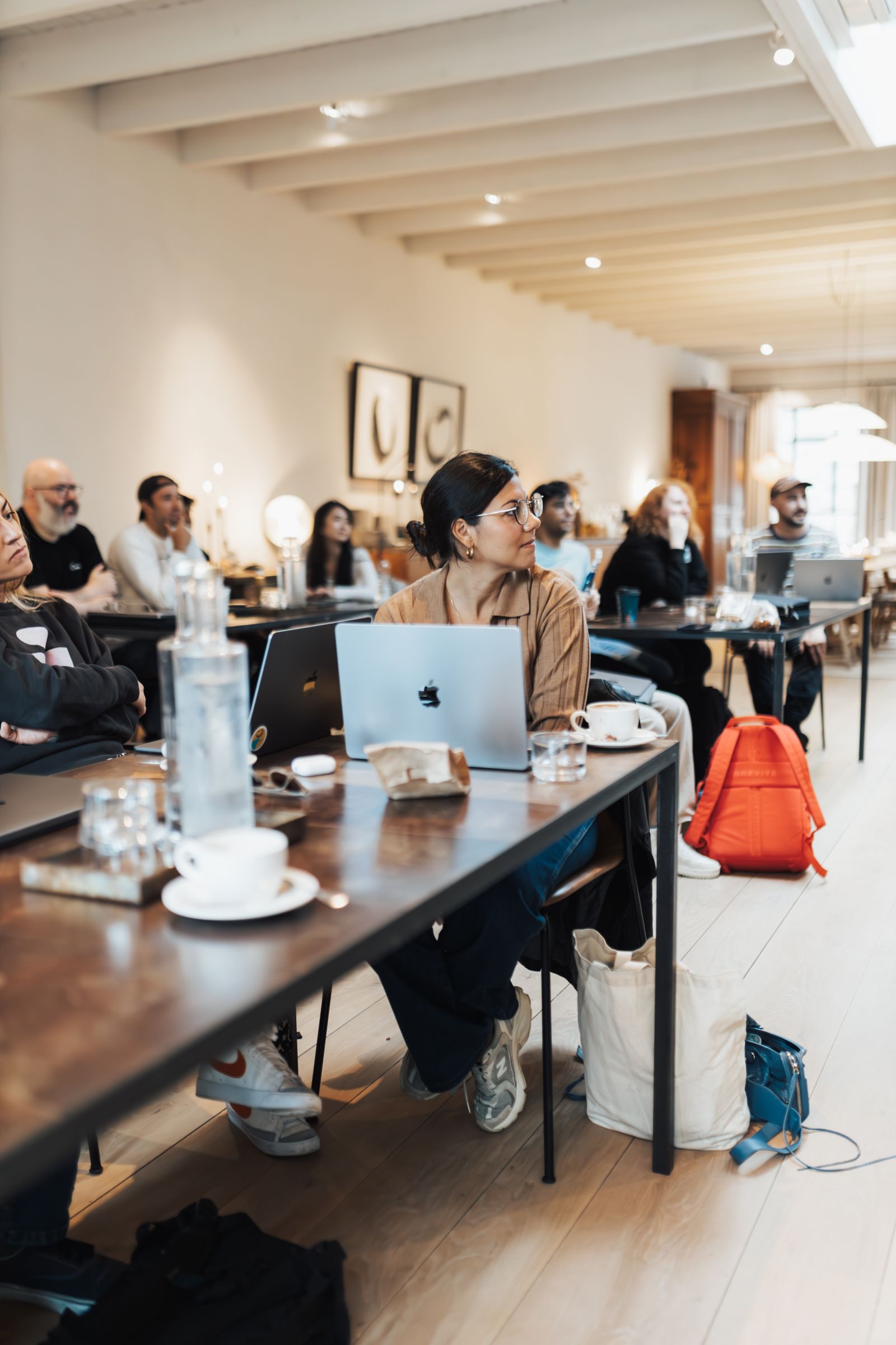 People with laptops at shared tables in a co-working space